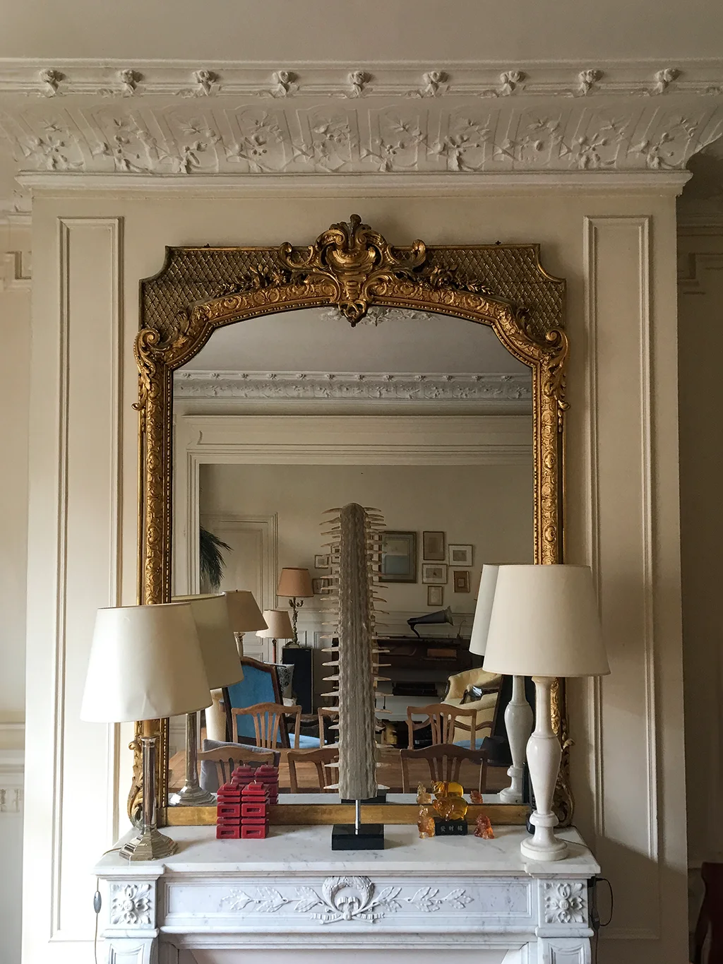 Grand miroir de trumeau en bois doré sculpté à fronton rocaille, posé sur une cheminée en marbre blanc, boiseries et plafond à stuc, style Napoléon III